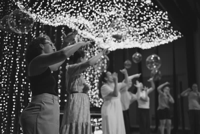 Alunos e professores em cena sob a cortina de luzes do palco