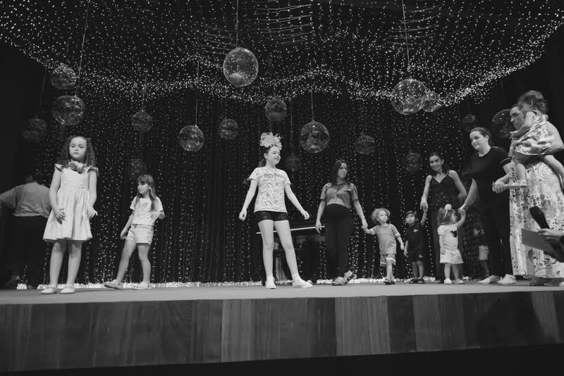 Turma infantil no palco com professores