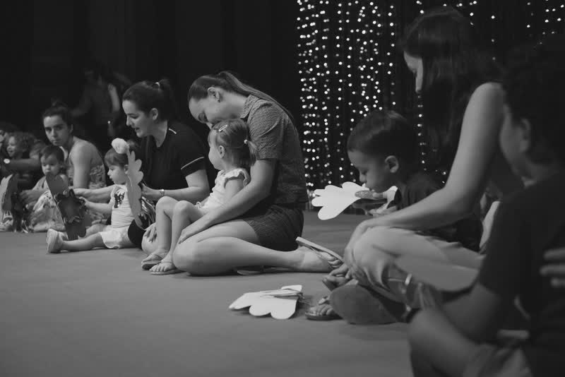 Crianças e mães sentadas no palco